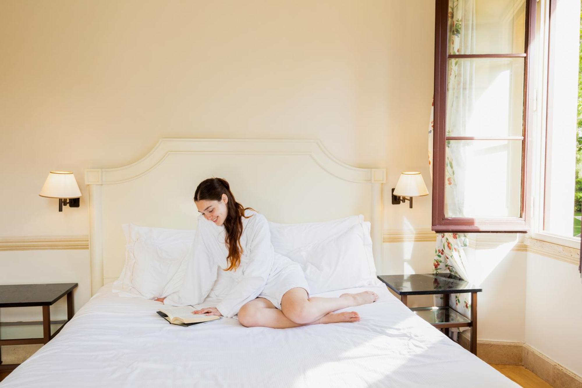 Qc Termeroma Spa And Resort Fiumicino Esterno foto A woman reading in bed